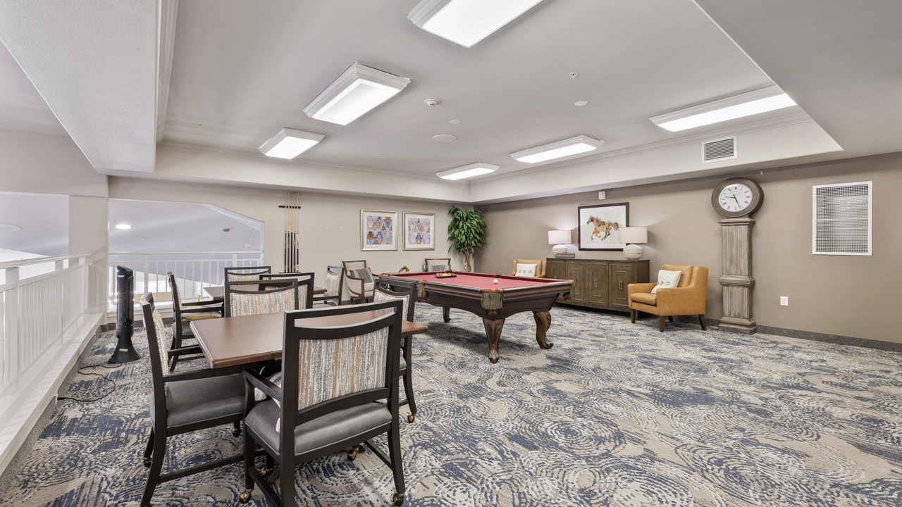 Spacious game room with a pool table, card table and chairs, and shelves along the walls.